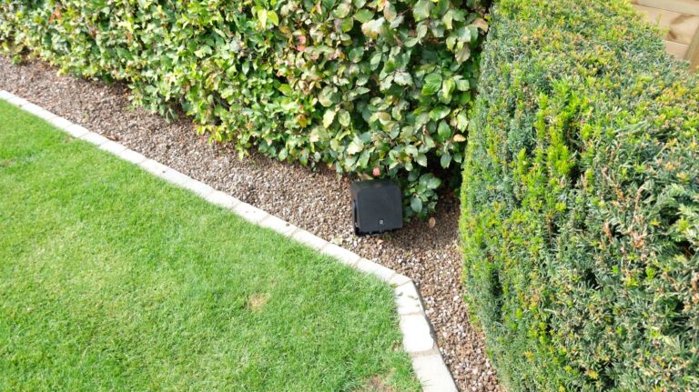 AUDAC VIRO5-luidspreker discreet geplaatst in de haag van een tuin te Voorde